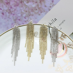 Sparkling silver and gold long tassel rhinestone earrings on elegant ceramic display