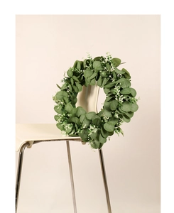 Close-up of green eucalyptus wreath with dense leaves hanging on a white modern chair