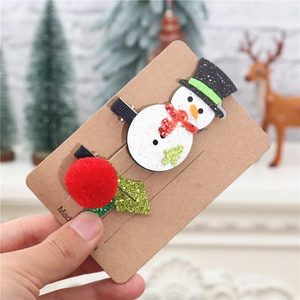 Close-up of glitter snowman and plush ball Christmas hair clips on brown card packaging