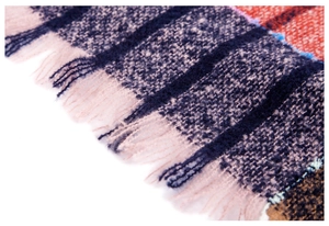 Macro detail of plaid textured knit fabric with pink and navy tassels on a hooded poncho