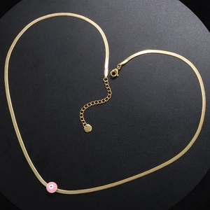 Detalle de cadena de serpiente dorada con colgante de ojo turco rosa y cierre de langosta