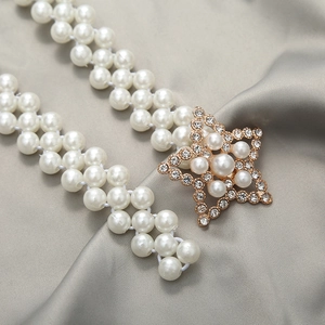 Detail of elegant star-shaped buckle with inlaid pearls and rhinestones on gold waist chain