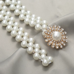 Close-up of pearl waist belt with gold flower buckle and sparkling rhinestones