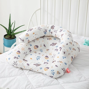 Multifunctional infant nursing pillow with colorful floral print on white quilted bed