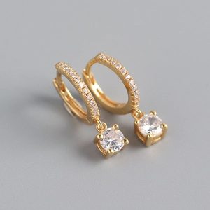 Macro detail of gold S925 sterling silver huggie earrings with round cubic zirconia