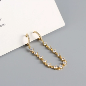 Macro view of gold S925 silver tassel earrings with shimmering cubic zirconia stones