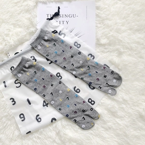 Detailed view of gray Tabi socks with colorful numeric patterns on a white plush background