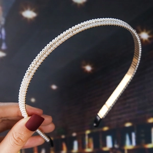 Detail of double-row pearl headband with sparkling rhinestones on golden metal base