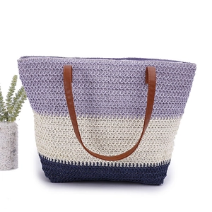 Detail of a woven tote bag featuring purple, beige, and navy stripes with brown leather handles