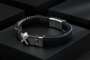 Close-up of black braided leather bracelet with silver stainless steel cross clasp and zircons