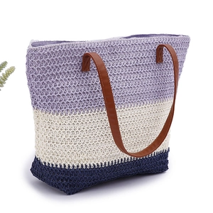 Woven beach tote bag with purple, cream, and navy blue stripes and brown leather handles