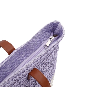 Purple woven beach shoulder bag with brown handles and a silver zipper closure