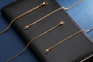 Detailed close-up of golden stainless steel chains with lobster clasps on black leather