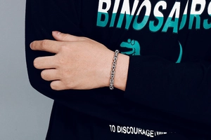 Close-up detail of silver braided interlocking chain link bracelet on male model wrist