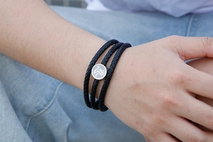 Detail of multi-layer braided leather bracelet with round stainless steel clasp on wrist