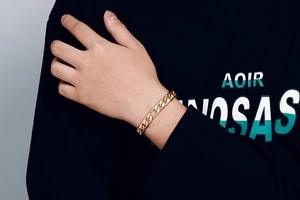 Gros plan d'un bracelet gourmette Figaro doré avec finition polie sur le poignet