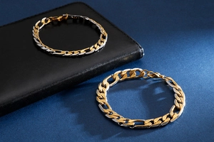 Gros plan du bracelet chaîne Figaro bicolore or et argent sur un fond texturé de qualité