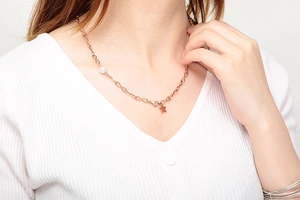Nahaufnahme der roségoldenen Stern-Halskette mit weißer Perle am Hals des Models
