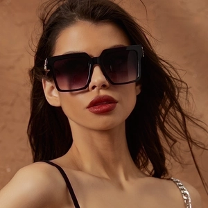 Close-up of black oversized square sunglasses with gradient purple lenses and metal details
