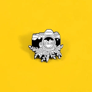 Creative black and white camera enamel pin with mountain landscape and floral details