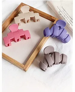 Detail of four matte textured geometric hair clips arranged on a wooden tray