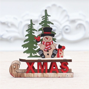 Detail der hölzernen Weihnachtsschlitten-Deko mit Schneemann und grünen Tannen
