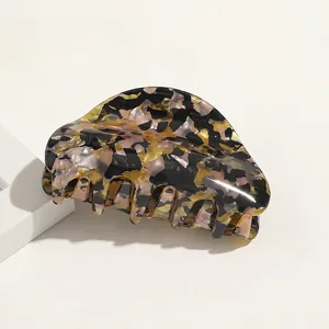 Detailed view of a tortoiseshell acetate hair claw clip with yellow and pink pattern