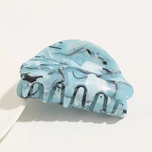 Detail of large acetate hair claw clip featuring blue and white marble pattern texture