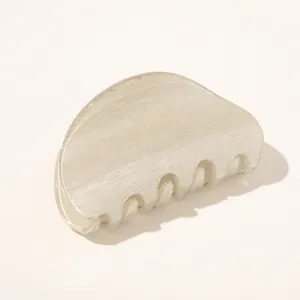 Close-up of a minimalist cream hair claw clip with pearlescent texture and rounded design