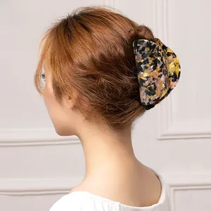 Detail showing marble texture acetate hair claw clip worn on a bun hair style