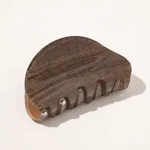 Detailed close-up of brown hair claw clip with faux wood grain texture and metal spring