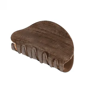 Macro detail of large dark brown hair claw clip with matte wood grain texture