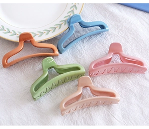 Detailed view of candy-colored hollow hair claws in five pastel shades on white fabric