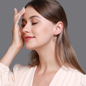 Détail d'élégantes boucles d'oreilles papillon dorées avec cristaux micro-pavés