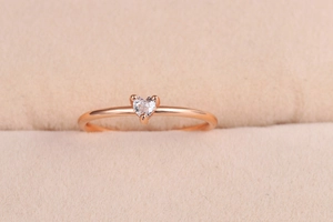 Dettaglio di un anello minimalista in oro rosa con zircone a forma di cuore su velluto