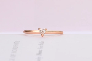 Macro di un anello in zircone a forma di cuore in oro rosa su una pagina di libro bianco