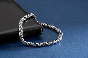 Detailed macro view of silver polished box chain bracelet with lobster clasp closure