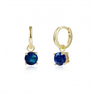 Detalle de aros dorados con colgantes de piedra azul y contraste S925