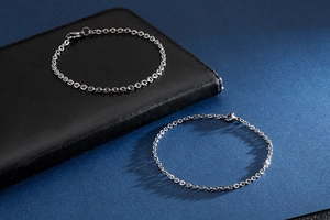 Detail of silver stainless steel chain bracelet with lobster clasp on a dark leather wallet