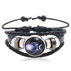 Detailed view of handmade multilayer black leather bracelet with starry nebula glass charm