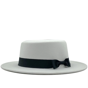 Close-up of white wool boater hat featuring a sleek black ribbon and side bow detail