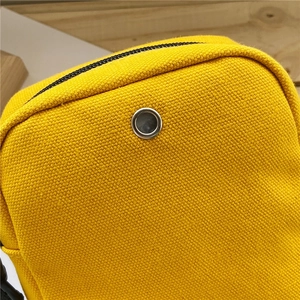 Detailed macro view of metal earphone hole and black zipper on yellow canvas bag
