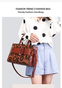 Detail of brown leather tote bag with embossed lettering and adjustable shoulder strap