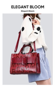 Deep red leather tote bag with embossed letters shown on a female model shoulder