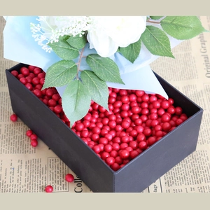 Artificial red berries and white flowers in a black gift box for festive home decoration