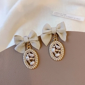 French vintage bow earrings with pearl oval pendants on elegant leather texture