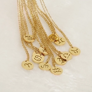 Detalle de collares de signos del zodiaco en oro de 18K sobre fondo de peluche blanco