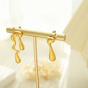 Pendientes asimétricos de metal líquido bañados en oro de 18K sobre soporte de exhibición