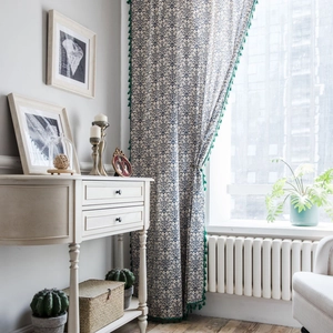 Blue and white porcelain print curtain with green tassels in a bright home setting