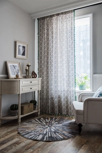 Detail of translucent curtain with blue porcelain pattern and green tassel trim accents